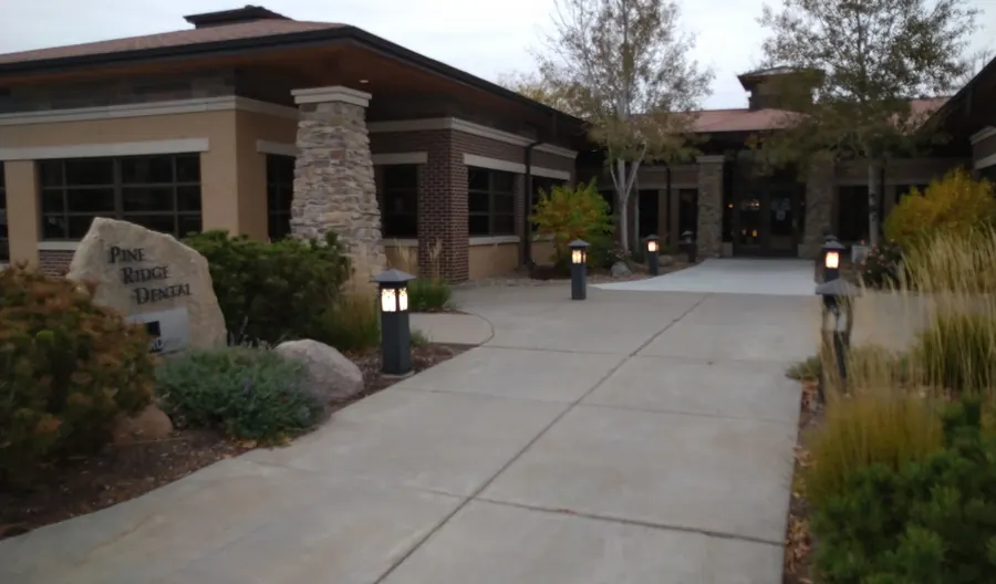 The walk to the Wilderness Ridge office on Executive Woods Drive, with a Pine Ridge Dental boulder sign and path lights.