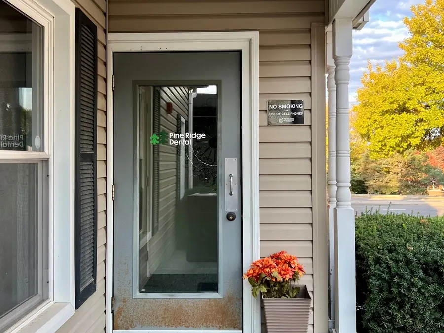 The front door of the Edgewood office, with the Pine Ridge Dental logo on the glass and autumn flowers beside it.