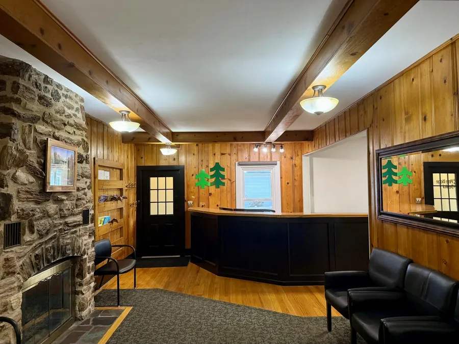 The reception area at Pine Ridge Dental, with knotty-pine walls, a stone fireplace and the pine-tree logo on the wall.